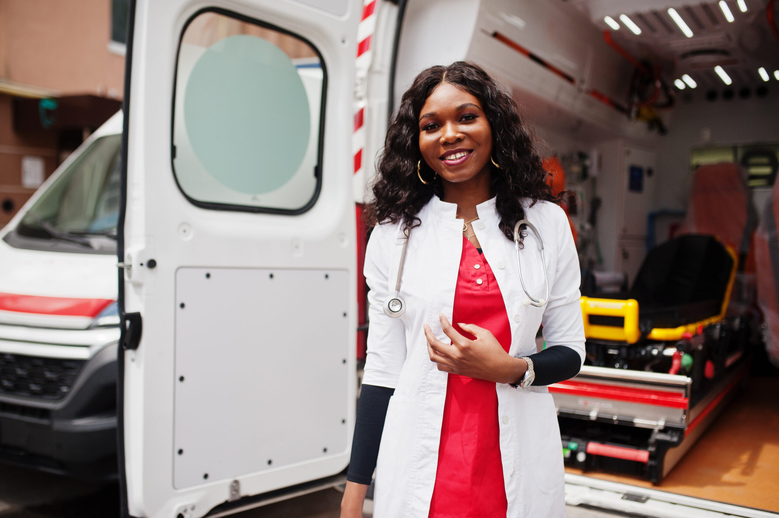 African american female paramedic standing in front of ambulance